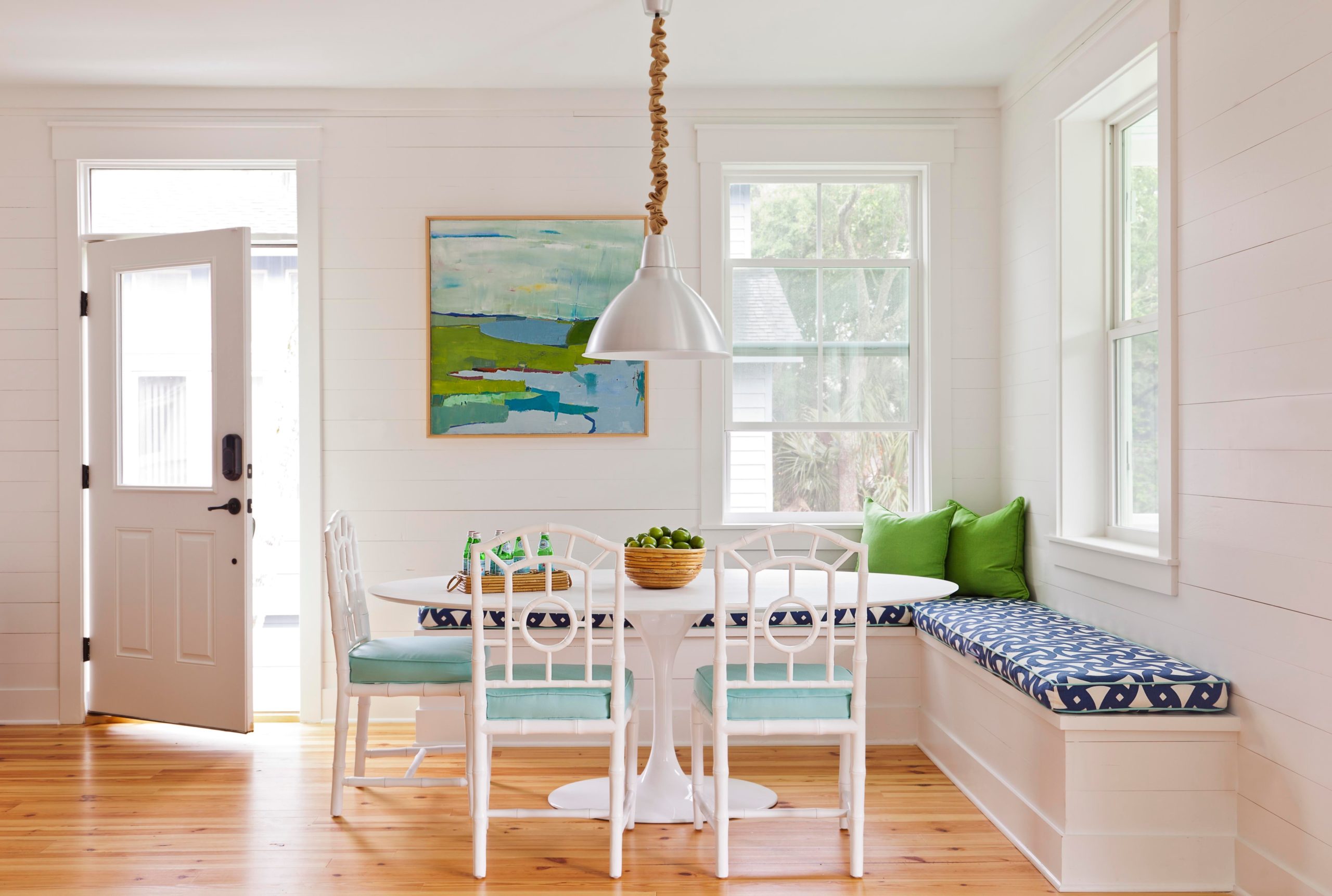 Sidney Wagner created this bright, functional dining nook. A large tulip table is surrounded by white dining chairs, a blue and white bench and green throw pillows.