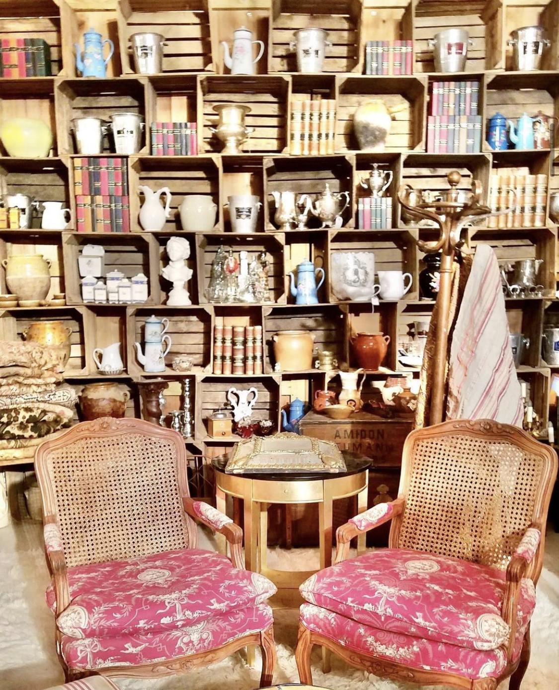 Rattan-backed Louis-style armchairs with shelves of decor and vintage books