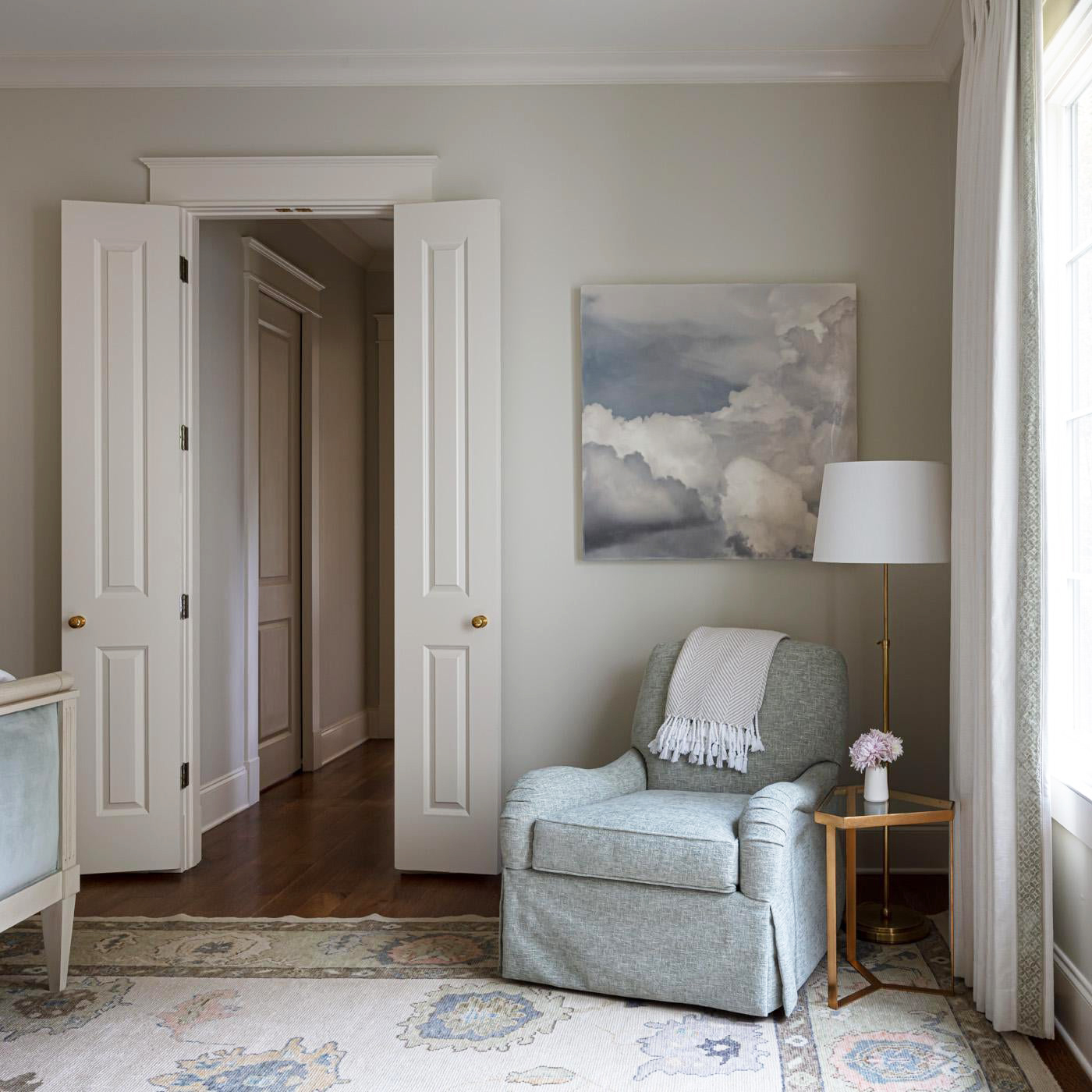 Comfy, oversized blue-gray armchair on textile rug with cloud painting.