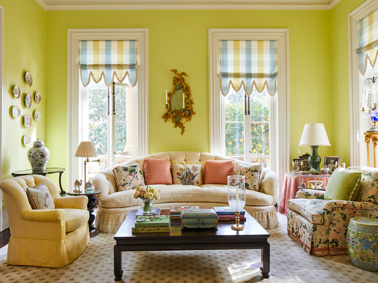 Bright yellow living room with curved tufted couch and floral armchair 