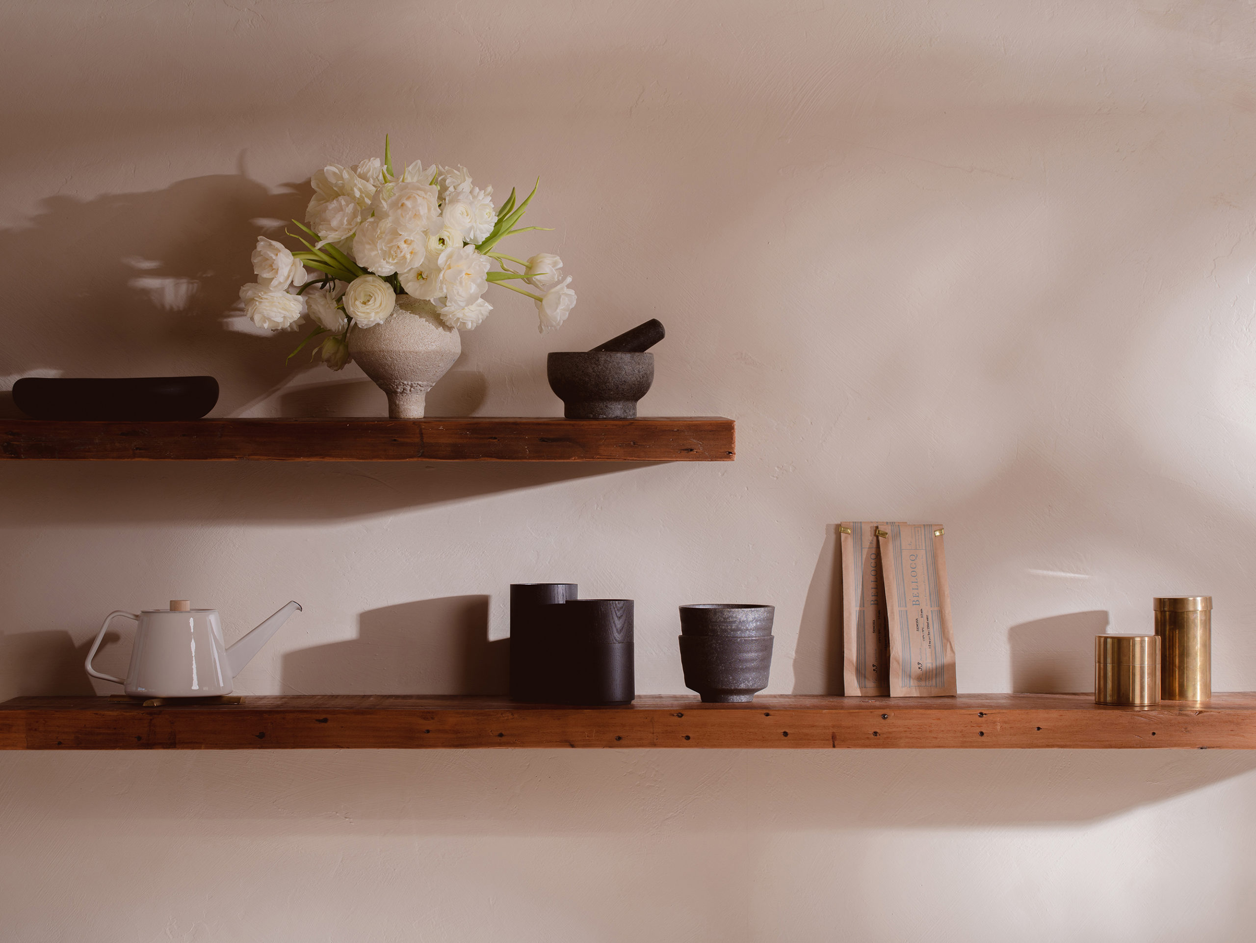 Open wood shelving with black and cream ceramics with brass jars