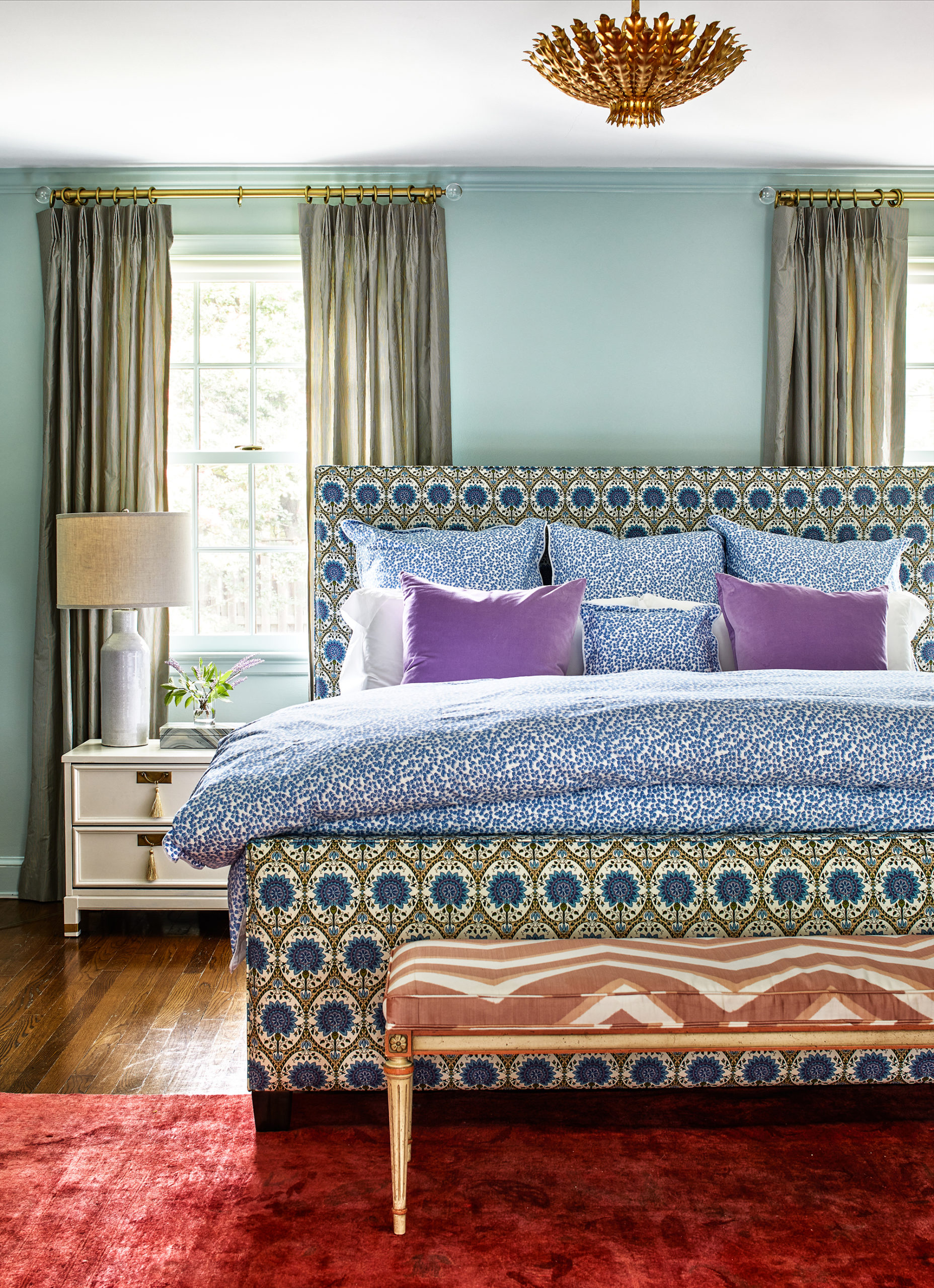 This bedroom features a bold-print bed frame with blue bedding and a red textured rug.