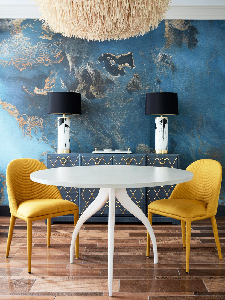 Blue dining room with blue side board and black and white table lamps with yellow dining chairs