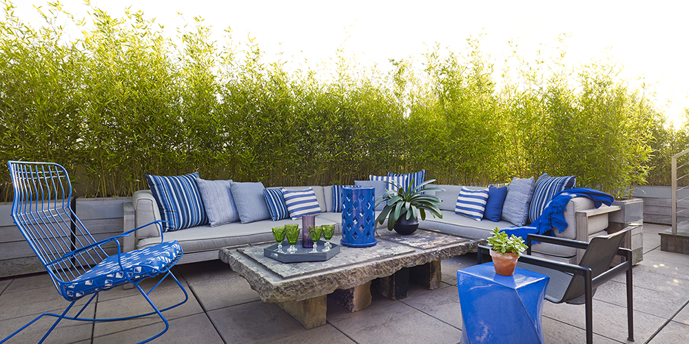 Outdoor sitting area with stone coffee table and blue wire rocking chair