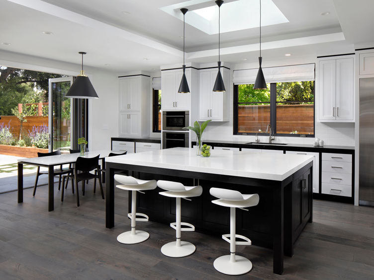 This minimalist kitchen features a completely black and white design with sleek pendant lights and futuristic bar stools.