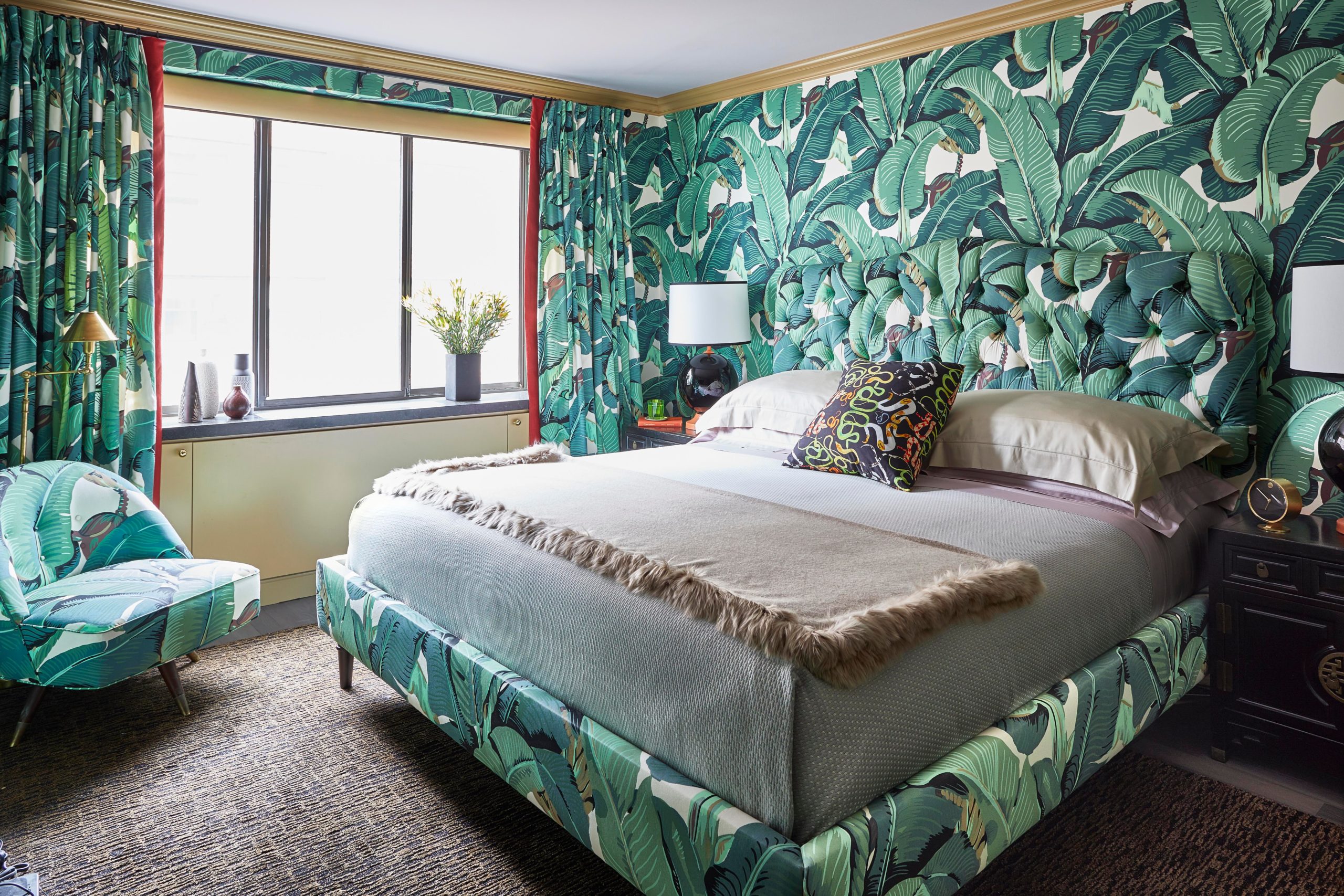 Bedroom with palm wallpaper, matching upholstered bed frame and accent chair, and beige throw.