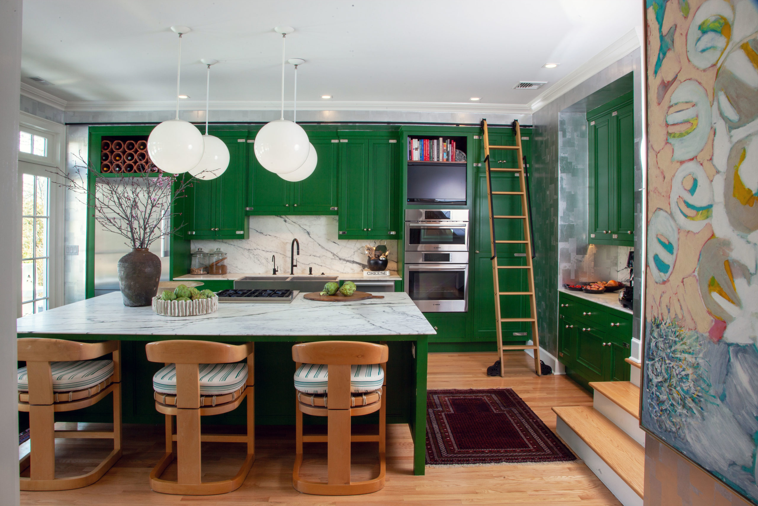 Contemporary kitchen with green cabinets, globe pendants, and wood counter stools