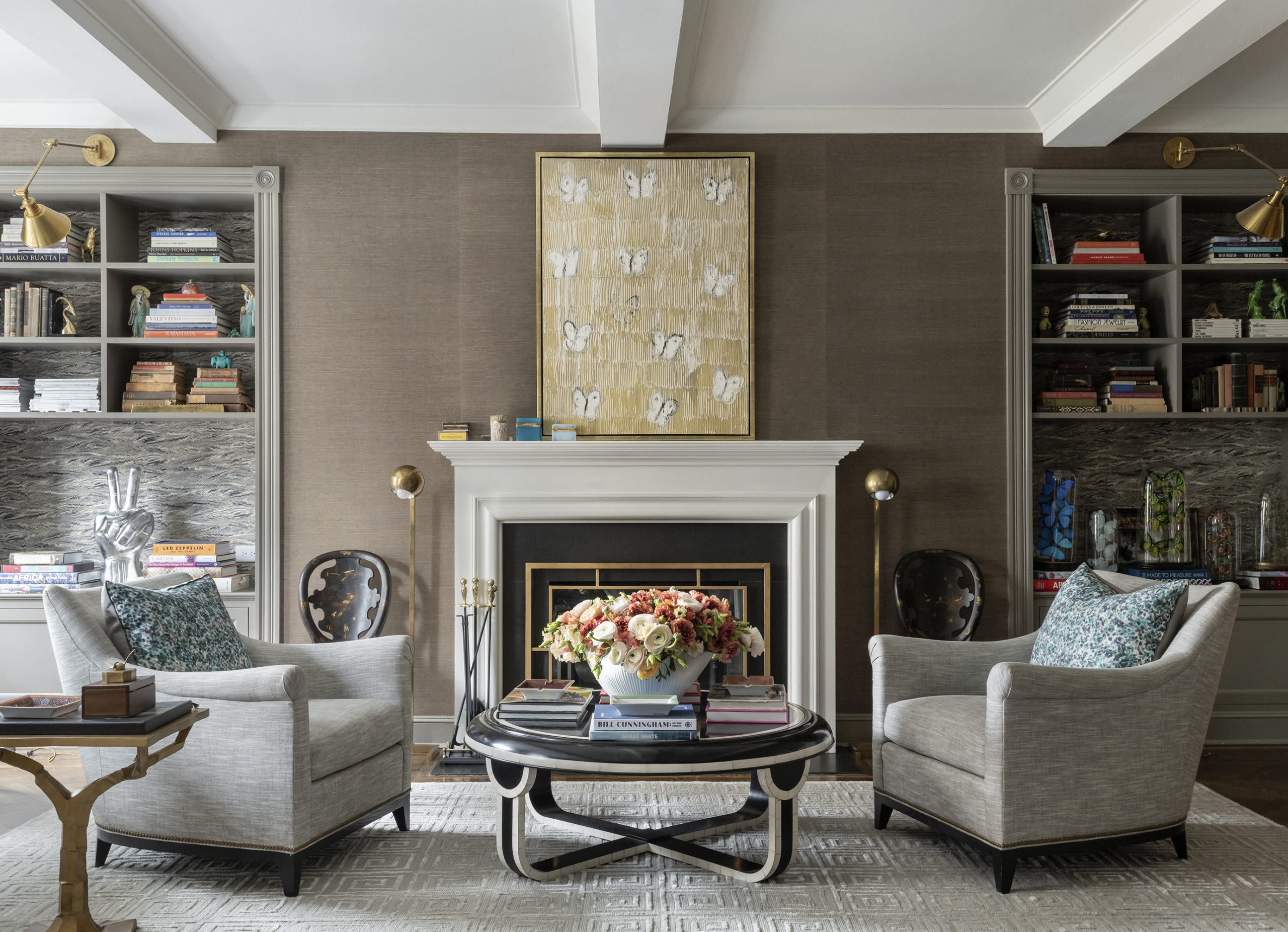 Brent Neale living room with round black and white coffee table, gray armchairs, and gold butterfly painting.