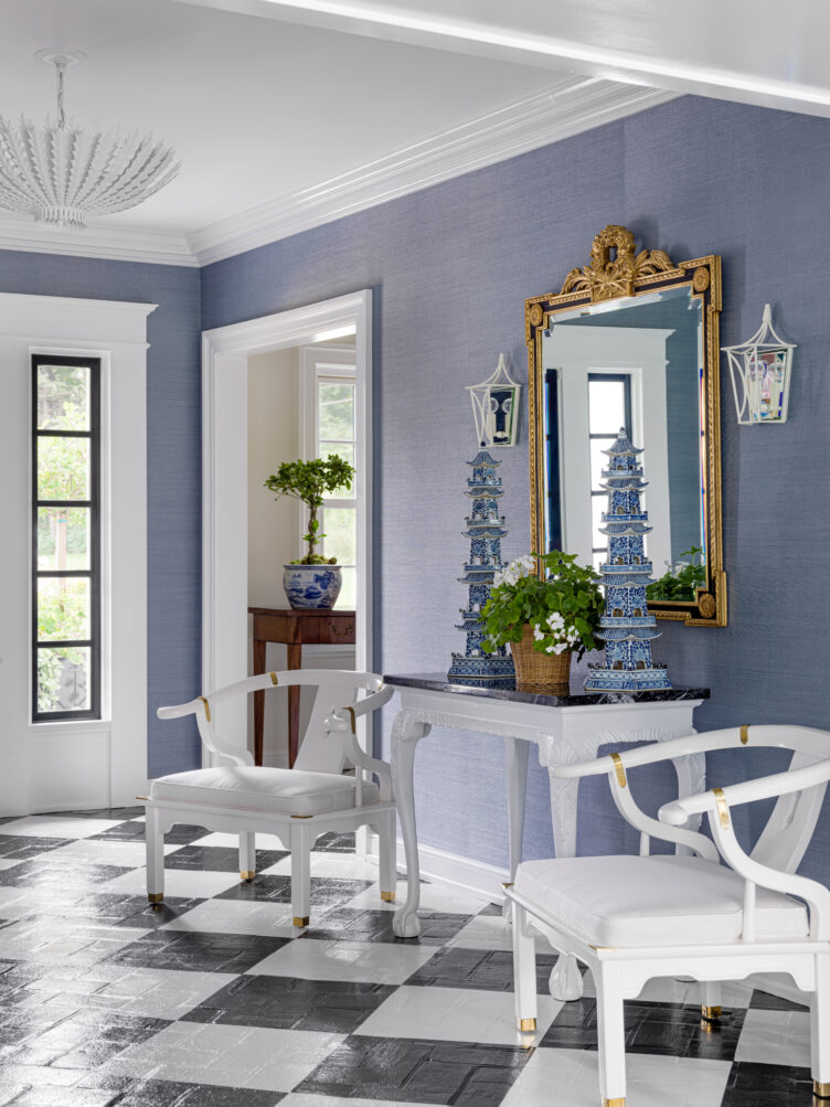 Blue wall-papered hallway with matching white armchairs and blue asian-inspired sculptures 