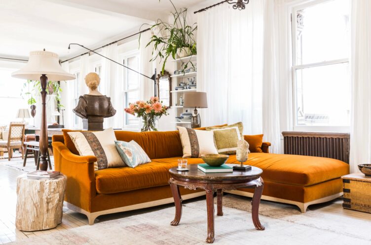 Orange velvet sectional and round wood coffee table with raw wood side table