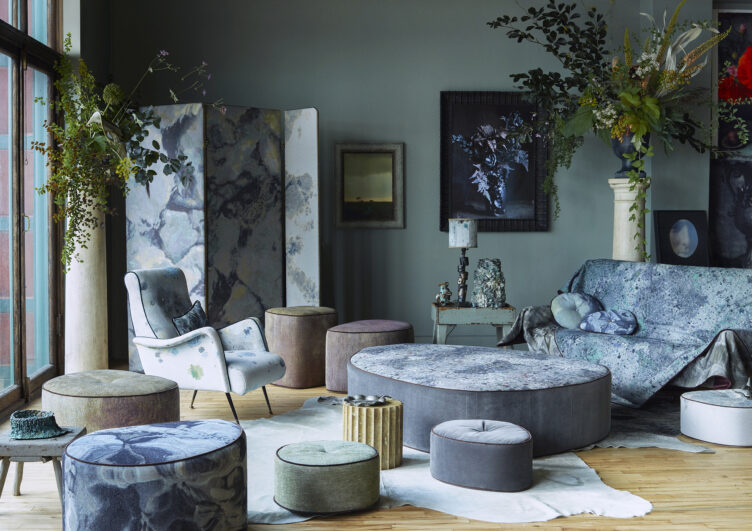 This blue living room features an array of floor cushions and ottomans with floral and paint-splattered textiles.