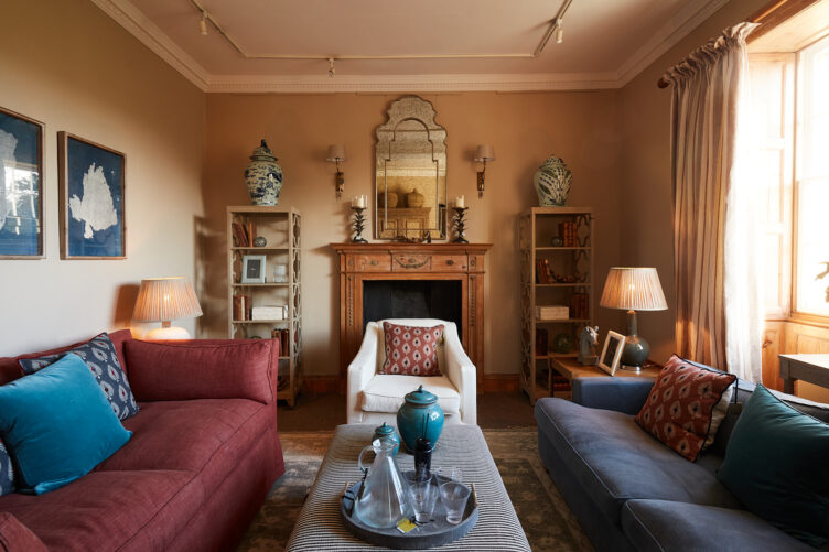 Cozy sitting room with wood fireplace, white armchair, and patterned throw pillows