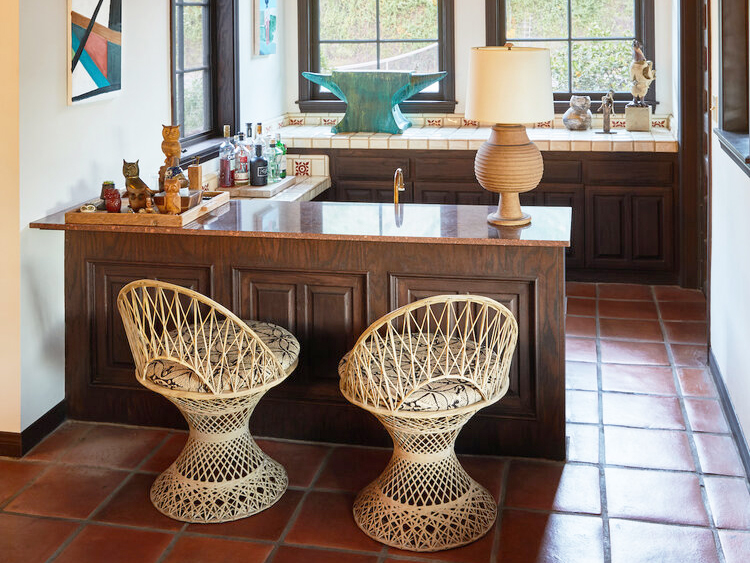 Bar area with wicker bar seats and dark wood cabinets with tiled countertop.