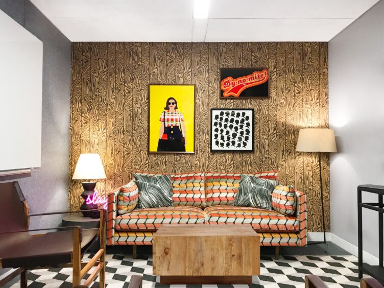 Seating area with psychedelic brown wallpaper, geometric rug, and patterned couch.