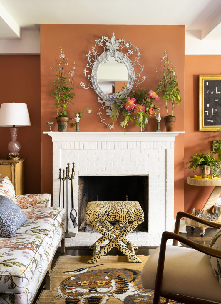 Orange living room with white fireplace and cheetah-print ottoman.