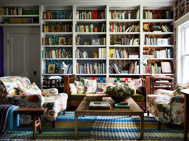 Eclectic living room with full bookshelves and floral armchairs 