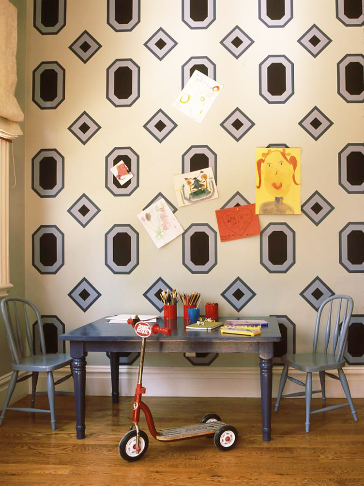 Kids table and chairs with geometric wallpaper and children's paintings