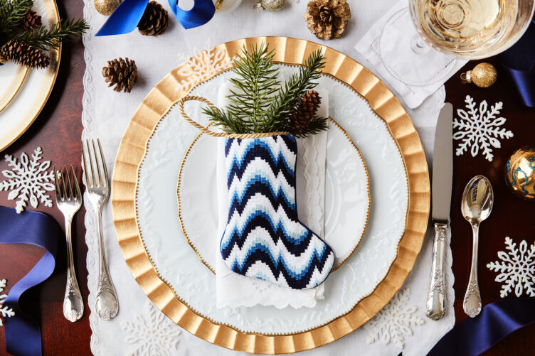 Gold rimmed china with antique silver utensils and blue zigzag bauble stocking.