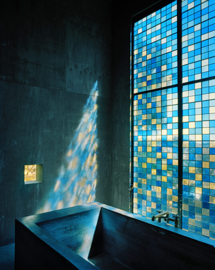 Bathroom with black basin tub and blue and yellow stained glass