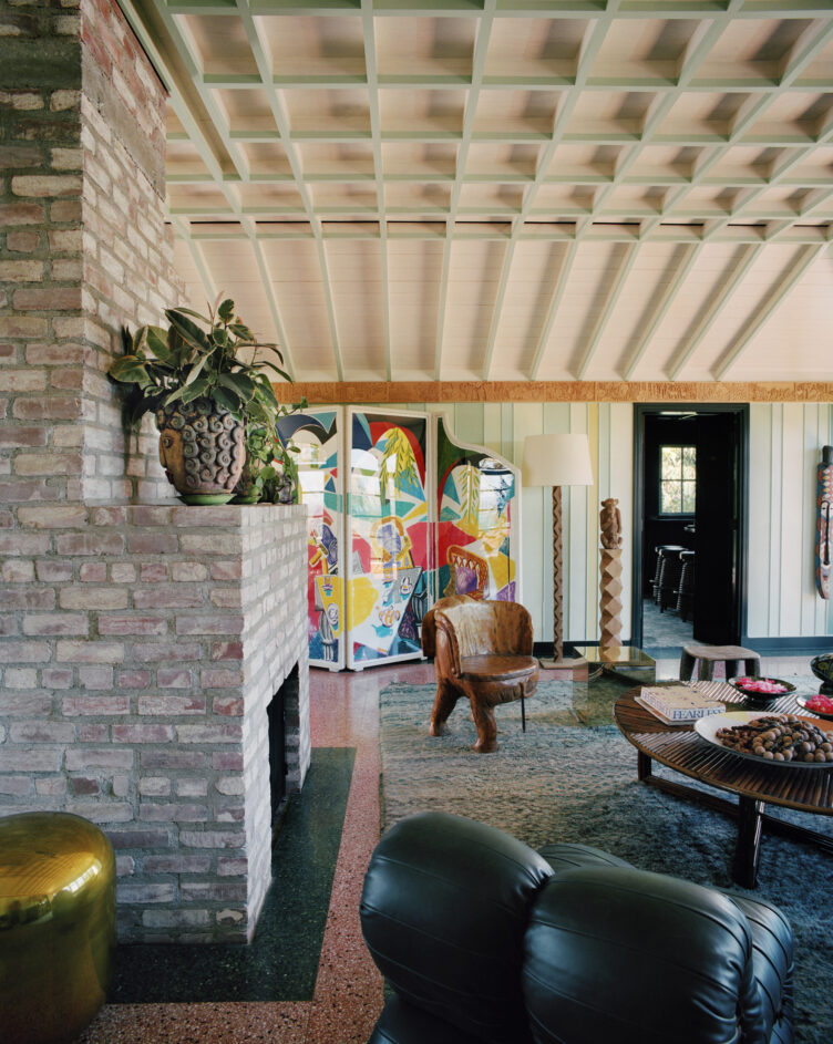 Seating area with brick fireplace, colorful room divider, and wood accent chair