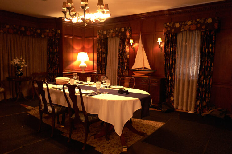 In this warm wood dining room, Wannop sourced Chippendale style chairs, a sailboat sculpture, and table lamp and chandelier. 