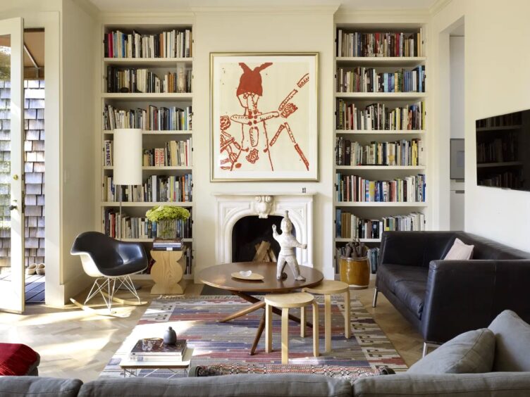 In this mid-century modern living room with a vintage fireplace, Martin Young Design used a rocking leather chair, a shaded floor lamp, and a mid-century modern side table. 