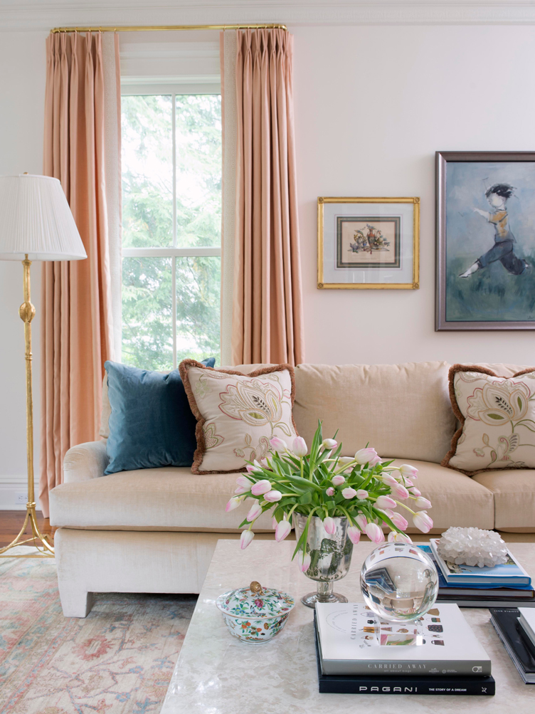 A Bright Living Room with a white sofa, pink curtain, and a pink wool rug