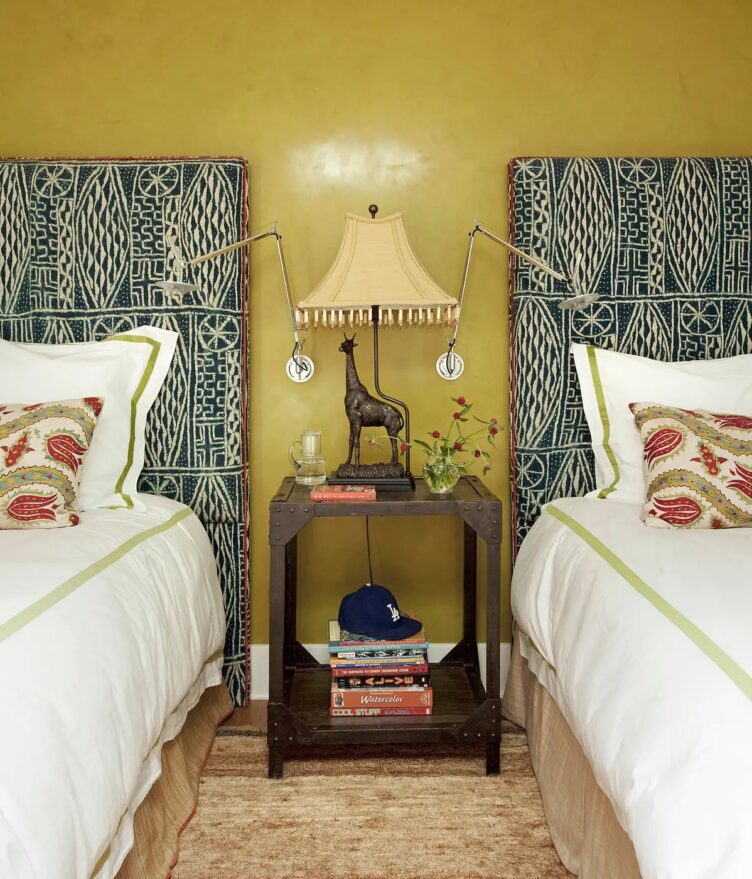 Bedroom with double beds, blue patterned headboards, yellow walls, and a giraffe lamp bedside